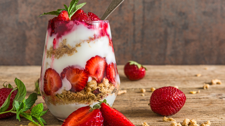 A yogurt parfait made with fresh strawberries, granola, and mint