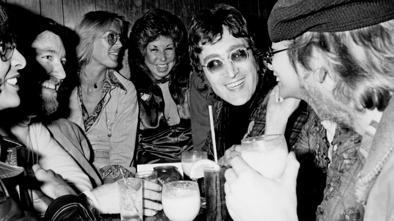 John Lennon in round glasses with others, with white cocktails
