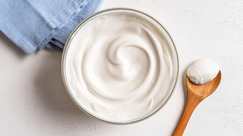 Bowl and spoon of sour cream next to a blue napkin