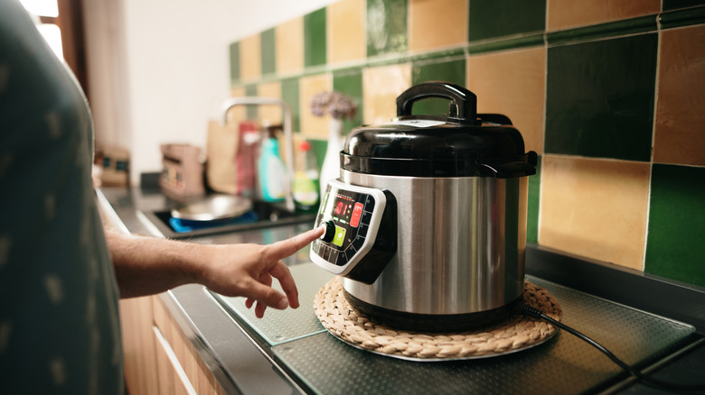 A hand programming an automatic slow cooker.