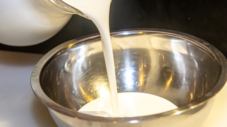 Heavy cream being poured into metal bowl
