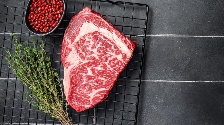 A top-down view of an uncooked Wagyu steak on a black wire tray