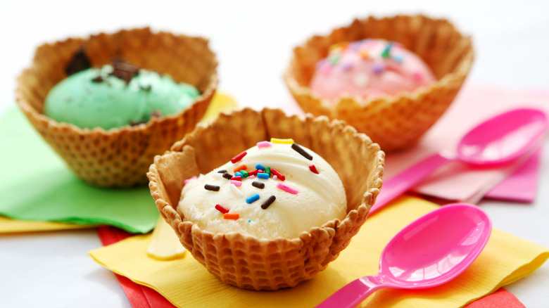 Three waffle cone cups with ice cream and pink spoons