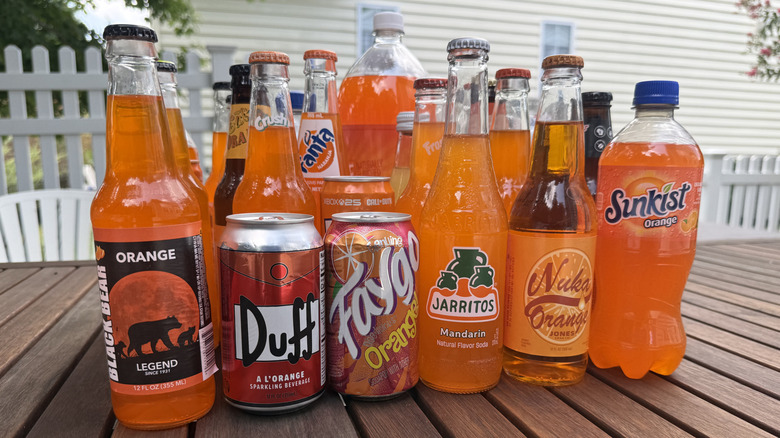 A row of orange soda cans and bottles