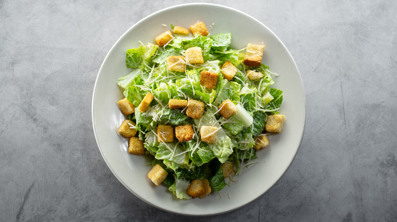 Caesar salad in white bowl on gray surface