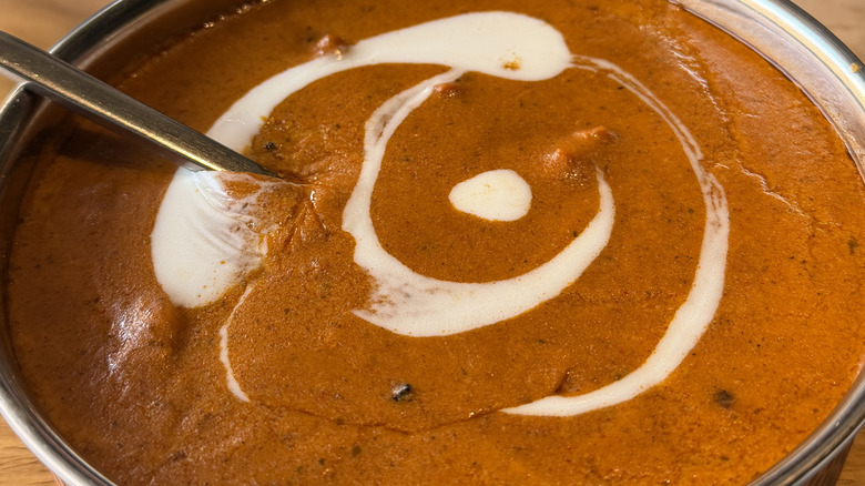 A bowl of red curry with a creamy swirl on top and a spoon