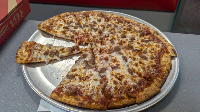 Chuck E. Cheese's sausage pizza with some slices missing on a metal dish