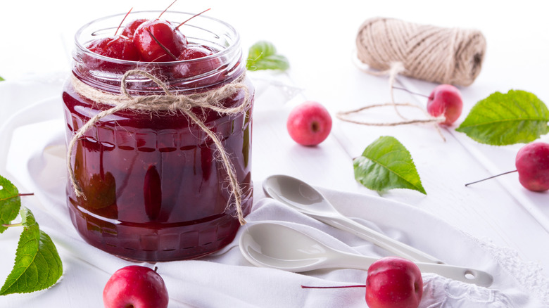 Crabapple jam in a jar with fresh crabapples and twine