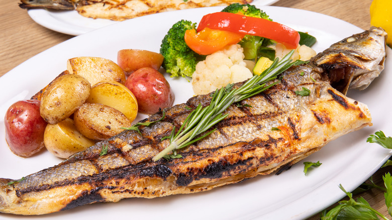 Whole grilled branzino with rosemary, roasted potatoes, and a side of veggies