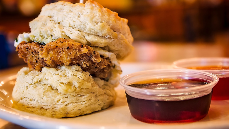 Maple syrup sitting next to chicken and biscuit