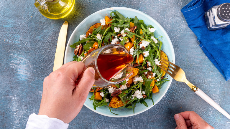 Pouring salad dressing on harvest salad