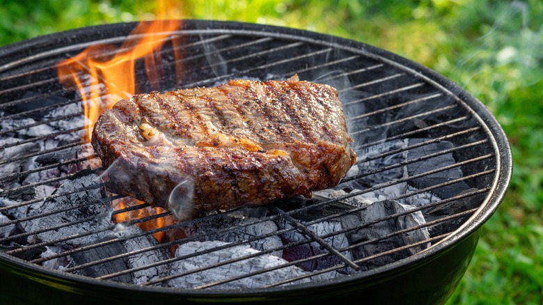 Beef steak grilling on charcoal grill