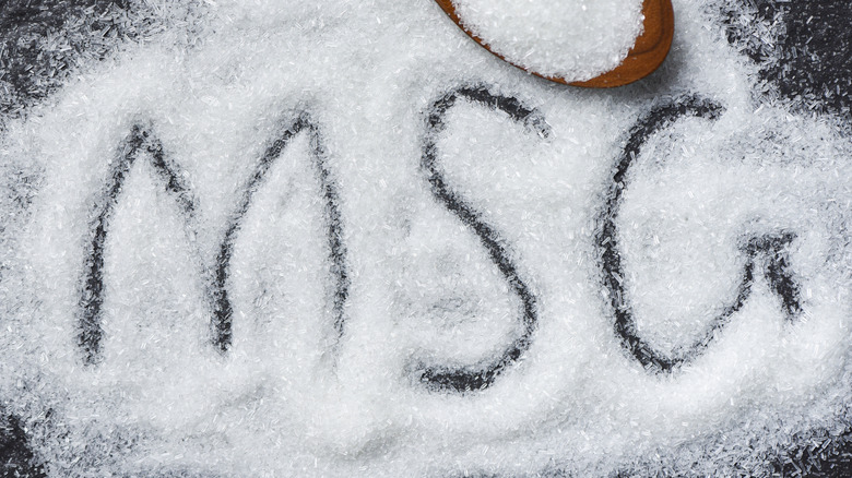 The letters MSG are written into a salt-like powder on a dark surface