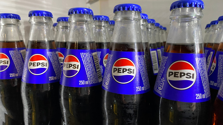 Glass bottles of Pepsi on a refrigerated shelf