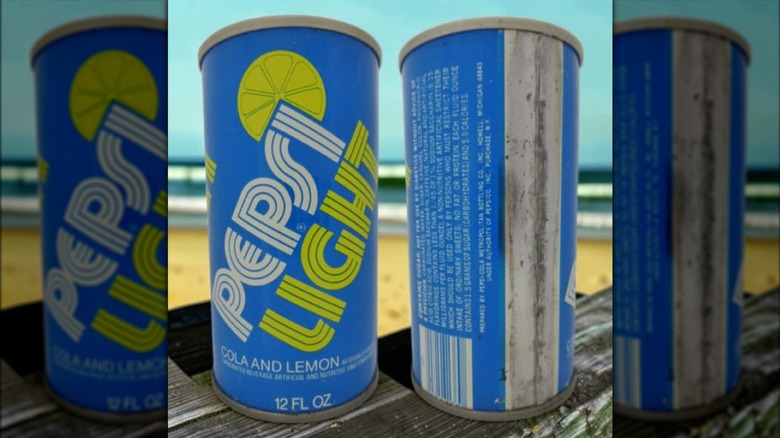 Blue cans of Pepsi Light on a picnic table with the beach in the background