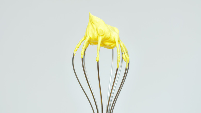 Yellow colored meringue on upside down whisk