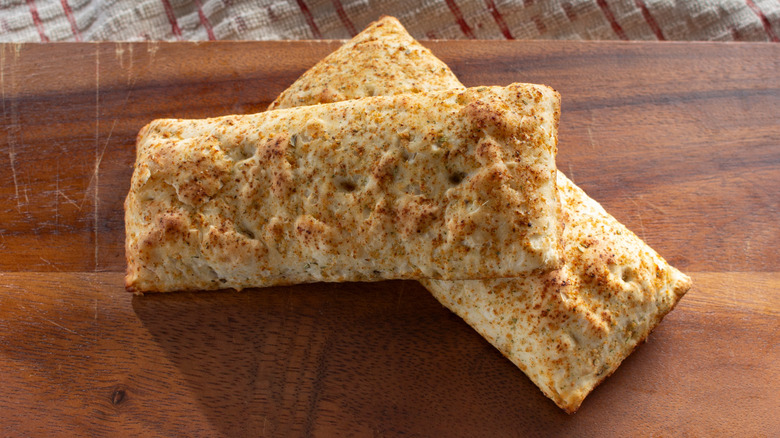 One hot pocket laid across another on a wooden board