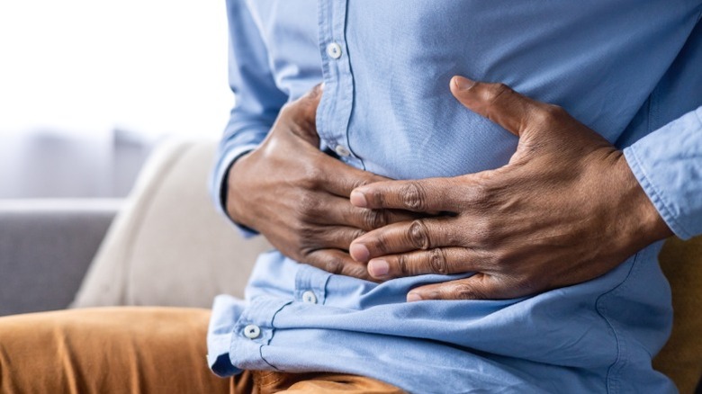 A person clutching their stomach in gastric distress.