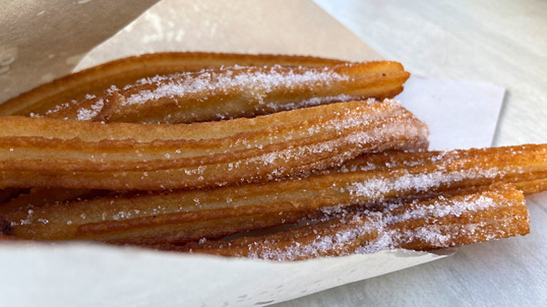 Churros powdered with sugar on paper wrapping