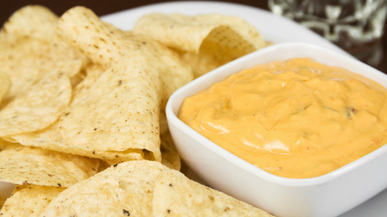 Nacho cheese in dipping bowl with a side of tortilla chips.