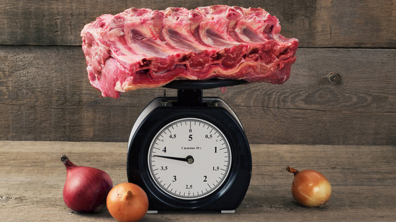 Raw meat on a scale surrounded by onions