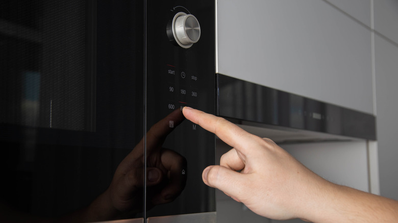 Someone pushing buttons on a microwave