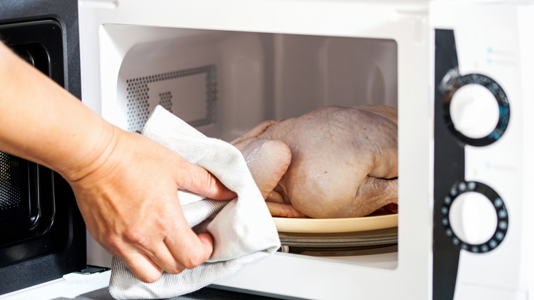 A whole chicken defrosting in a microwave