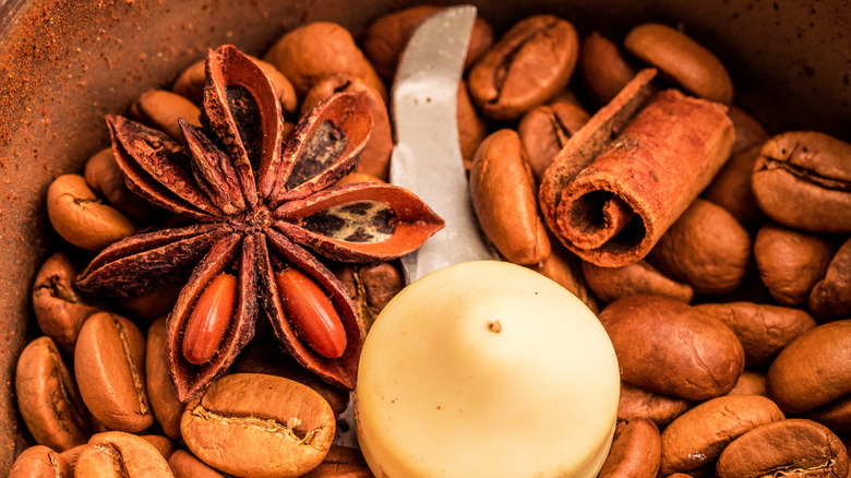 Close up whole spices and coffee beans in electric coffee grinder