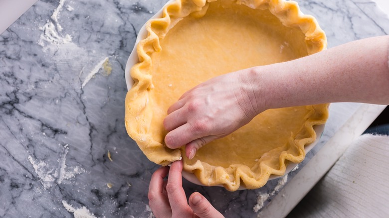 A baker shaping a pie crust.