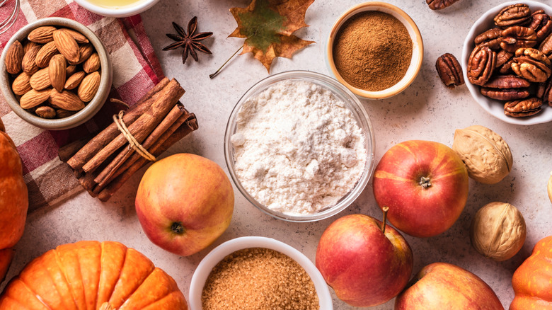 Apples, nuts, spices, sugar and flour spread out on surface fall themed