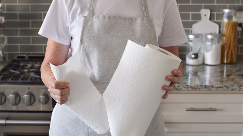 Woman is tearing a piece of paper towel in a kitchen at home.