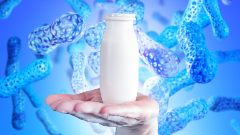 A hand holding a jar of yogurt