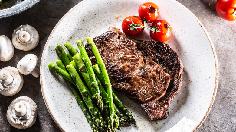 Grilled steak with asparagus, tomatoes, and mushroom sauce
