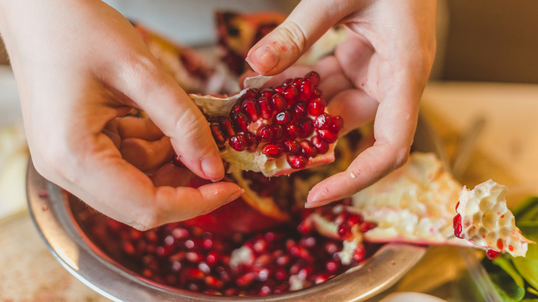 A close-up of a person deseeding a pomegranate.