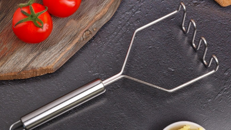 Potato masher on counter near tomatoes