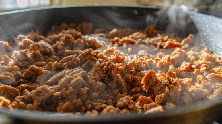 Ground beef in a skillet with steam