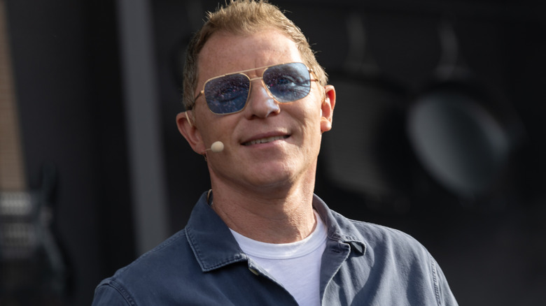 Bobby Flay wears sunglasses and a microphone at an event