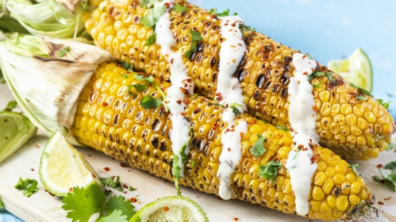 Grilled corn on the cob topped with a drizzle of crema, cilantro, lime, and spices.