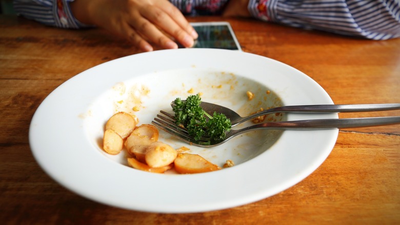 White bowl with meal leftovers in front of restaurant customer
