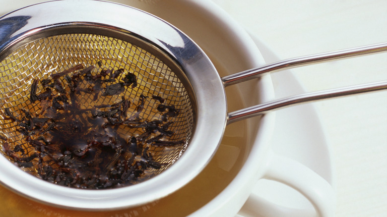 Tea leaves being strained from a cup of tea