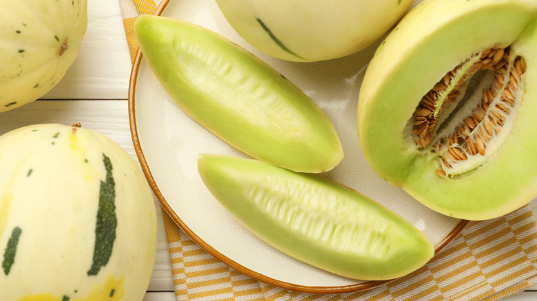 Whole and cut honeydew melon on a plate