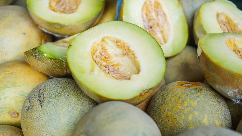 A pile of honeydew melons, with some cut open