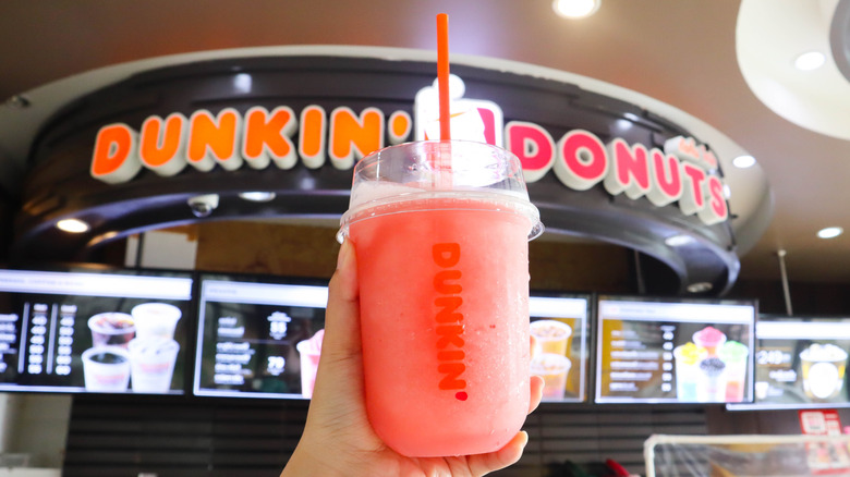 A Dunkin' Coolatta in front of a Dunkin' Donuts sign and menu.