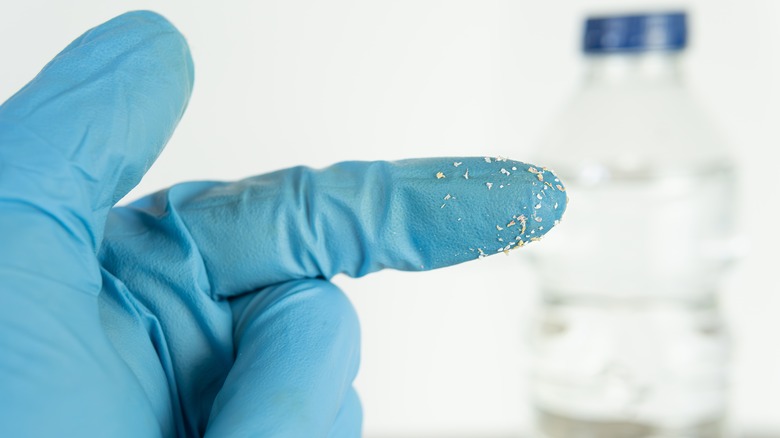 Hand of scientist wearing gloves with microplastic shavings.