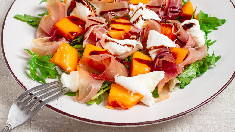 Prosciutto and cantaloupe salad with fresh cheese, greens, and balsamic vinegar