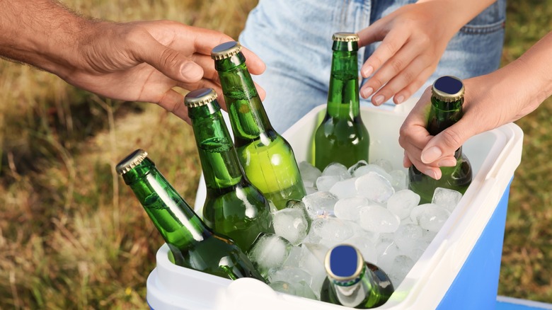 People grab bottled drinks from an ice cooler