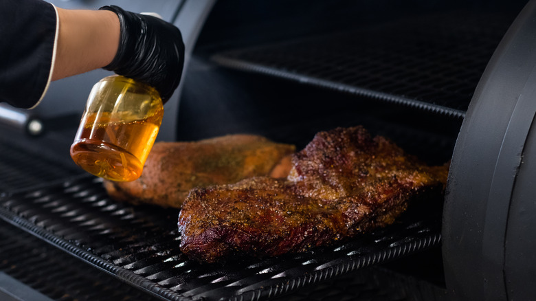 hand squirting grilled meat with liquid