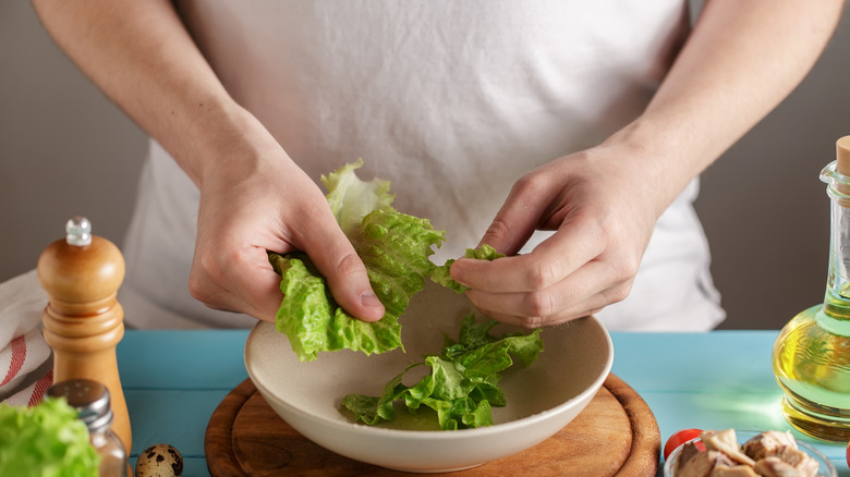 Hands tearing lettuce by hand into bowl