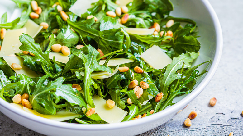 Arugula salad in a bowl with parmesan cheese and pine nuts