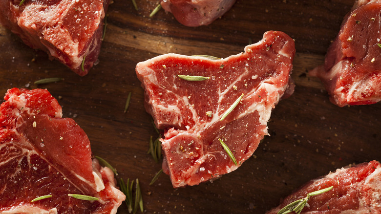 Lamb loin chops that've been sprinkled with rosemary and pepper on top.